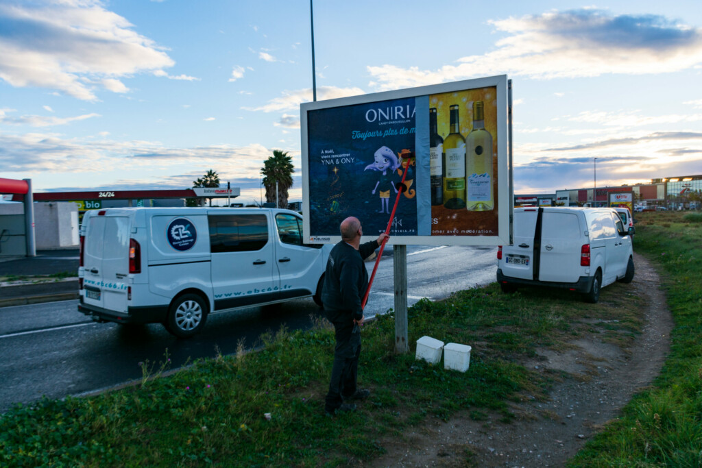 homme qui pose une affiche publicitaire